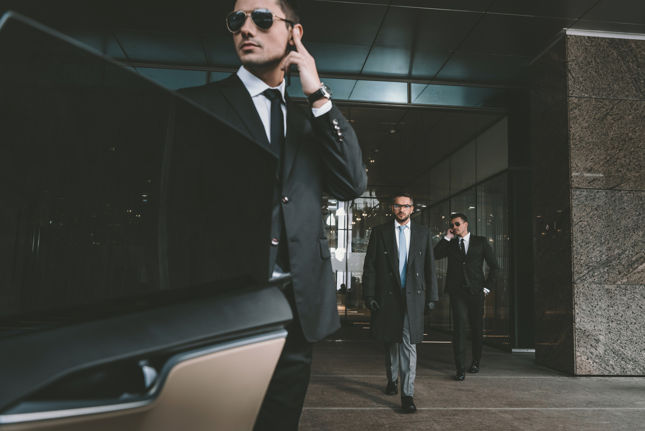 bodyguard opening car door for businessman